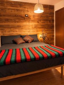 a bedroom with a bed with a wooden wall at Casa Cappuccetto in Imer