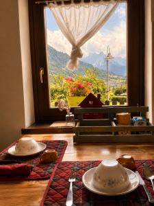 a table with plates and utensils in front of a window at Casa Cappuccetto in Imer