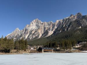 a mountain with a lodge in front of a lake at Chalet Al Lago in San Vito di Cadore