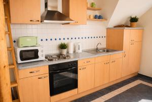 a kitchen with wooden cabinets and a sink and a microwave at Fehn Appartement II - Stay Apartment nahe Zentrum, Küche, Parkplatz & Highspeed WLAN in Papenburg