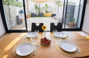 a table with plates and glasses and a bowl of fruit at Casa Elegante V3 Moderna 2 Suítes, Jardim e Garagem Privados in Olhão