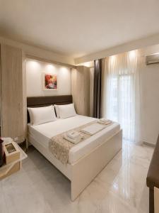 a bedroom with a large white bed and a window at Myrto Rooms in Pefkochori