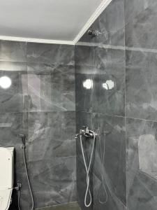 a bathroom with a shower with a stone wall at Vila Topi in Vlorë