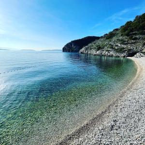 a beach with a rocky shore and the ocean at Apartman sa suncem in Beli +6 photos