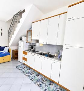 a kitchen with white cabinets and a sink at Leoncorno la Marina a Villasimius in Villasimius