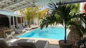 a swimming pool with chairs and a palm tree next to it at Villa Chanalu in Ngaparou