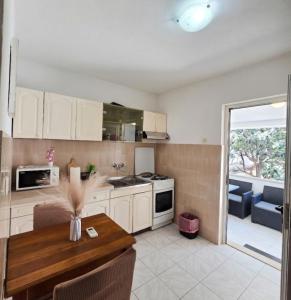 a kitchen with white cabinets and a wooden table at Apartmani Franceska in Bol