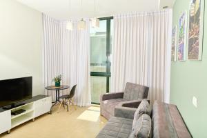 a living room with a couch and a tv and a table at H7 TLV in Tel Aviv