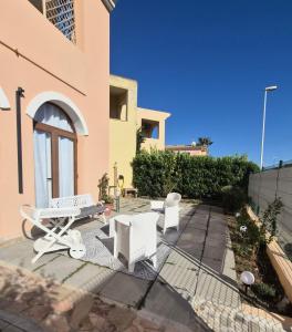 a patio with two white chairs and a table at Leoncorno la Marina a Villasimius in Villasimius
