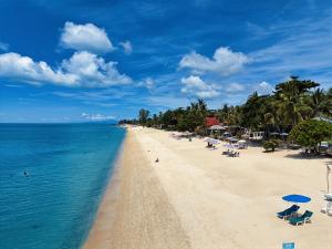 a beach with chairs and umbrellas and the ocean at Jasmine Garden Bungalow in Lamai