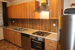 a kitchen with wooden cabinets and a stainless steel refrigerator at Furmint Vendégház in Tállya