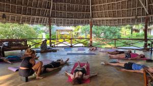 a group of people doing yoga in a pavilion at Mawimbi Bungalows in Nungwi