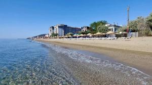 a beach with white chairs and the water at Gold in Confort hotel in Barbaros