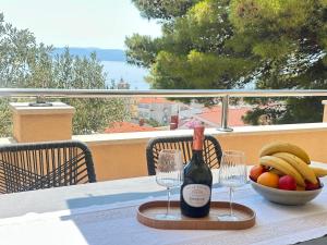 a table with a bottle of wine and a bowl of fruit at Apartmani Eterović in Baška Voda