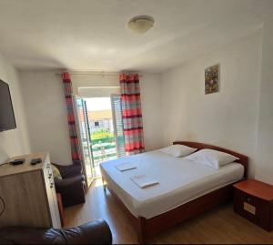 a bedroom with a bed and a couch and a window at Apartmani Franceska in Bol