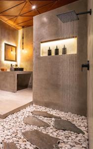 a bathroom with a shower with a pebble floor at Atol Villas in Uluwatu +12 photos