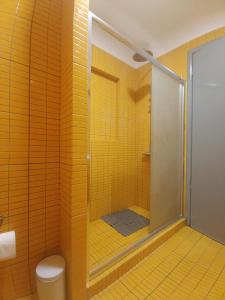 a yellow tiled bathroom with a shower and a toilet at Dioskouros Hostel in Athens +63 photos