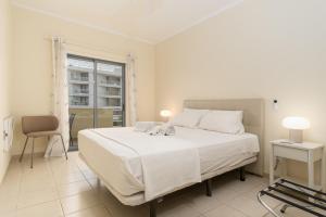 a white bedroom with a large bed and a window at Ria Olhao in Olhão