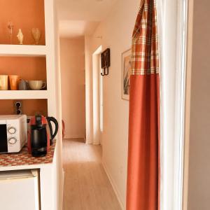 a kitchen with an orange curtain in a room at Bernadette' Cosy Flat - 3 minutes walk main door to sanctuary entrance- Old Town - Bernadette de Soubirous's neighborhood - Chapel for Prayer on site in Lourdes +36 photos