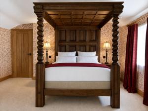 a bedroom with a large bed with a wooden canopy at Scale Hill Hotel in Loweswater