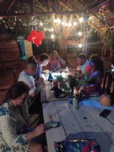 a group of people sitting around a wooden table at Nimal's white house in Nilaveli