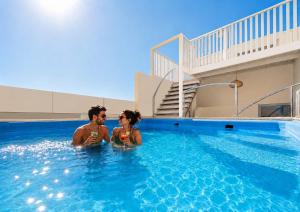 a man and woman sitting in a swimming pool at DAR-VIDA Guesthouse in Imsouane