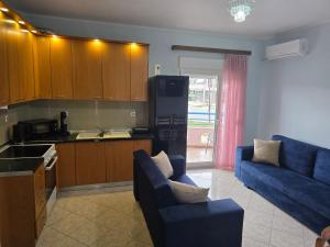 a living room with a blue couch and a kitchen at KSD apartment in Kallithea Halkidikis