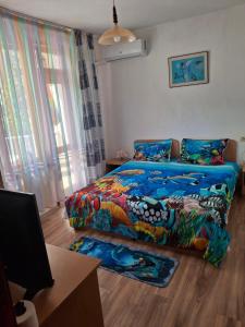 a bedroom with a bed with a colorful comforter at Къща за Гости Тера in Kiten