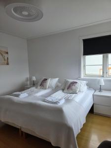 a white bedroom with a large bed and a window at Kríukot íbúð in Hólmavík