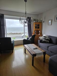 a living room with a table and a view of the ocean at Kríukot íbúð in Hólmavík