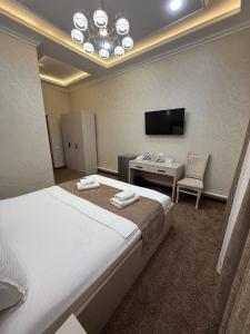 a hotel room with a bed and a desk and a television at Toj Mahal Hotel in Takchilik