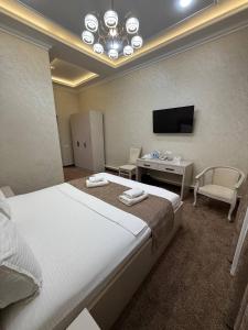 a bedroom with a bed and a desk and a television at Toj Mahal Hotel in Takchilik