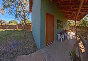 a porch of a house with a table and chairs at Chalé Jardim Mágico in Milho Verde