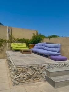 a patio with purple and green pillows and rocks at Les oliviers in Lédignan