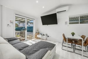 a living room with a couch and a tv on the wall at Lovely Hidden Gem in Redcliffe in Redcliffe