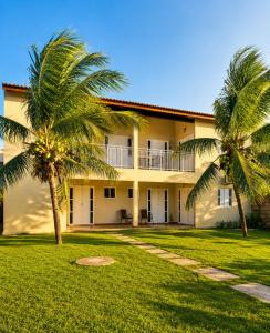 a building with two palm trees in front of it at Brisa do Preá- 700m da Praia do Preá -12km de Jeri in Prea