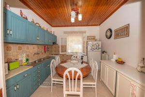 a kitchen with blue cabinets and a table and chairs at Ilia's Holiday Home in Perítheia