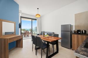 a kitchen and dining room with a table and a refrigerator at Kritamo Suites Sandy Bay in Ayia Napa