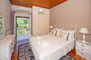 a bedroom with a white bed and a window at Ilia's Holiday Home in Perítheia