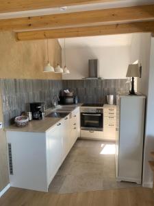a kitchen with white cabinets and a stainless steel refrigerator at Fewo Fernblick in Much +16 photos