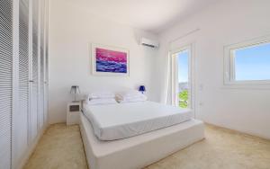 a white bedroom with a bed and a window at Sunset Flower Villa in Kástron