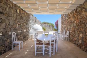 a stone walled patio with a white table and chairs at Sunset Flower Villa in Kástron