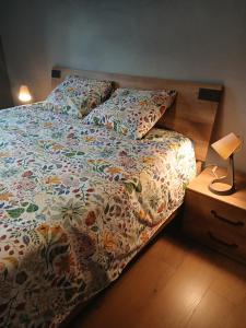 a bed with a colorful comforter and pillows on it at Le petit Broux in Aywaille