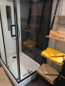 a glass shower with a yellow towel on a shelf at Le petit Broux in Aywaille