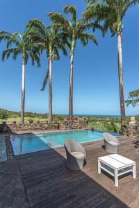 a pool with two chairs and a table and palm trees at Villas ti creole nogent in Sainte-Rose