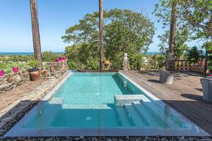 a swimming pool with blue water in a backyard at Villas ti creole nogent in Sainte-Rose
