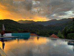 a swimming pool with a sunset in the mountains at Wonderland Resort Chiangmai in Chiang Mai