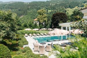 ein Bild von einem Pool mit Stühlen und Sonnenschirmen in der Unterkunft Hotel Bräu in Zell am Ziller
