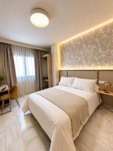 a bedroom with a large white bed and a desk at Zarú Hotel Boutique in Mocejón