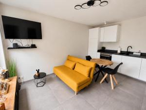 a living room with a yellow couch and a table at Gîte La Petite Villette in Fronville
